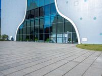 the entrance to a building that is white and blue with geometric shapes on it and grass in front of it