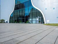 the entrance to a building that is white and blue with geometric shapes on it and grass in front of it