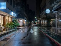 an empty city street during the rain in the night time with a person passing through it