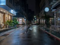 an empty city street during the rain in the night time with a person passing through it