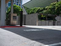 an empty, empty street with trees in the background and a sidewalk with a stop sign on the left side