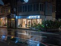 an empty store with a few lights lit up at night on a city street in the rain