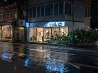 an empty store with a few lights lit up at night on a city street in the rain