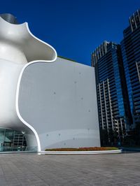 a white building with a large window in it is very tall and has a metal structure in front