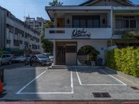 a small white building with lots of parked cars in it and a tall sign that says cookie sakuraya