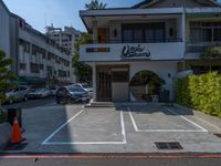 a small white building with lots of parked cars in it and a tall sign that says cookie sakuraya