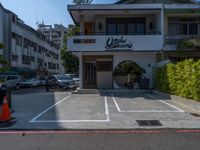 a small white building with lots of parked cars in it and a tall sign that says cookie sakuraya