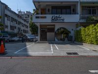 a small white building with lots of parked cars in it and a tall sign that says cookie sakuraya