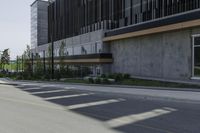 a tall cement building sits on an empty street with parking spaces in front of it