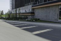 a tall cement building sits on an empty street with parking spaces in front of it