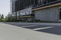 a tall cement building sits on an empty street with parking spaces in front of it