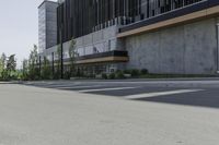 a tall cement building sits on an empty street with parking spaces in front of it