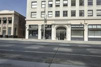 a very tall, white building on the corner of a city street with windows and doors