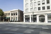 a very tall, white building on the corner of a city street with windows and doors