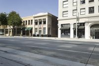 a very tall, white building on the corner of a city street with windows and doors