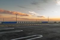 a parking lot with lines painted on it as the sun sets over the water and in the distance, near an ocean