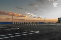 a parking lot with lines painted on it as the sun sets over the water and in the distance, near an ocean