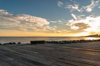 wooden boards with stones and sea in the background at sunset, seen from the top of an oceanfront walkway