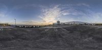 a wide angle view of a parking lot with a sunset in the distance of the sky