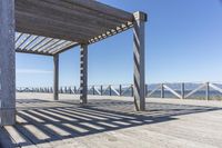 a bench sits under the shade on the pier, overlooking the water and mountains in the distance