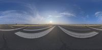 a wide angle view of an airport runway with the sun setting behind it and people standing on the tarmac