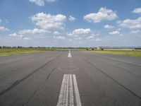 an empty runway with two circles in the middle of it with blue skies and clouds above