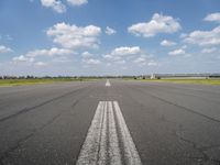 an empty runway with two circles in the middle of it with blue skies and clouds above