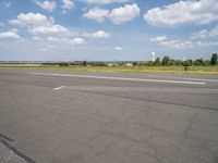 an airport runway and an airfield with lots of grass and clouds in the sky on a sunny day