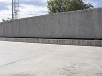 a large cement block wall next to a tall concrete tower and television mast in the distance