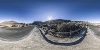 a man riding a motorcycle on top of a dirt road next to a mountain side