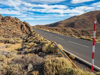 an open road in the desert with two red and white stripes running along it,