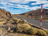 an open road in the desert with two red and white stripes running along it,