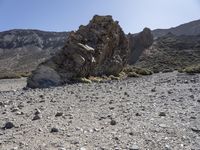 a desert with large rocks and grass near the top of a mountain with no one sitting on the rocks