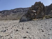 a desert with large rocks and grass near the top of a mountain with no one sitting on the rocks