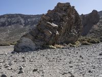 a desert with large rocks and grass near the top of a mountain with no one sitting on the rocks