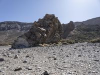 a desert with large rocks and grass near the top of a mountain with no one sitting on the rocks