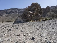 a desert with large rocks and grass near the top of a mountain with no one sitting on the rocks