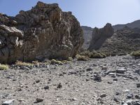 a desert with large rocks and grass near the top of a mountain with no one sitting on the rocks