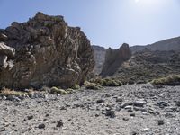 a desert with large rocks and grass near the top of a mountain with no one sitting on the rocks