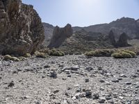 a desert with large rocks and grass near the top of a mountain with no one sitting on the rocks