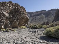 a desert with large rocks and grass near the top of a mountain with no one sitting on the rocks