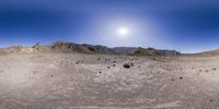 an panorama image of a desert with dirt on the ground and mountains in the background