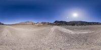 the large field in the middle of the desert near rocks and snow capped mountains looks like an alien world