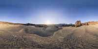 a panorama of a desert with hills and rocks in the background and a small circle shape made by a lens on the right side