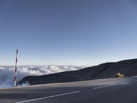 a road leading into the clouds, with a stop sign in the foreground and a mountain in the back