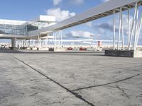 concrete floors on an airport terminal with lots of metal structures and buildings behind them on a sunny day