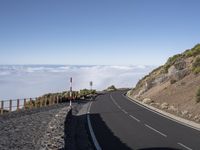 the road is winding toward the ocean in this mountainous area, while clouds are passing overhead