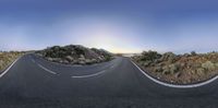 a highway curves around an island in the desert at dusk as the sun rises over the horizon