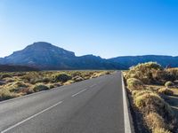 an empty highway in the middle of mountains and a clear sky with clouds above it