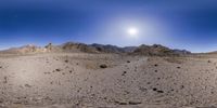 a panorama of mountains, desert, and rocks on a sunny day and sky in the background